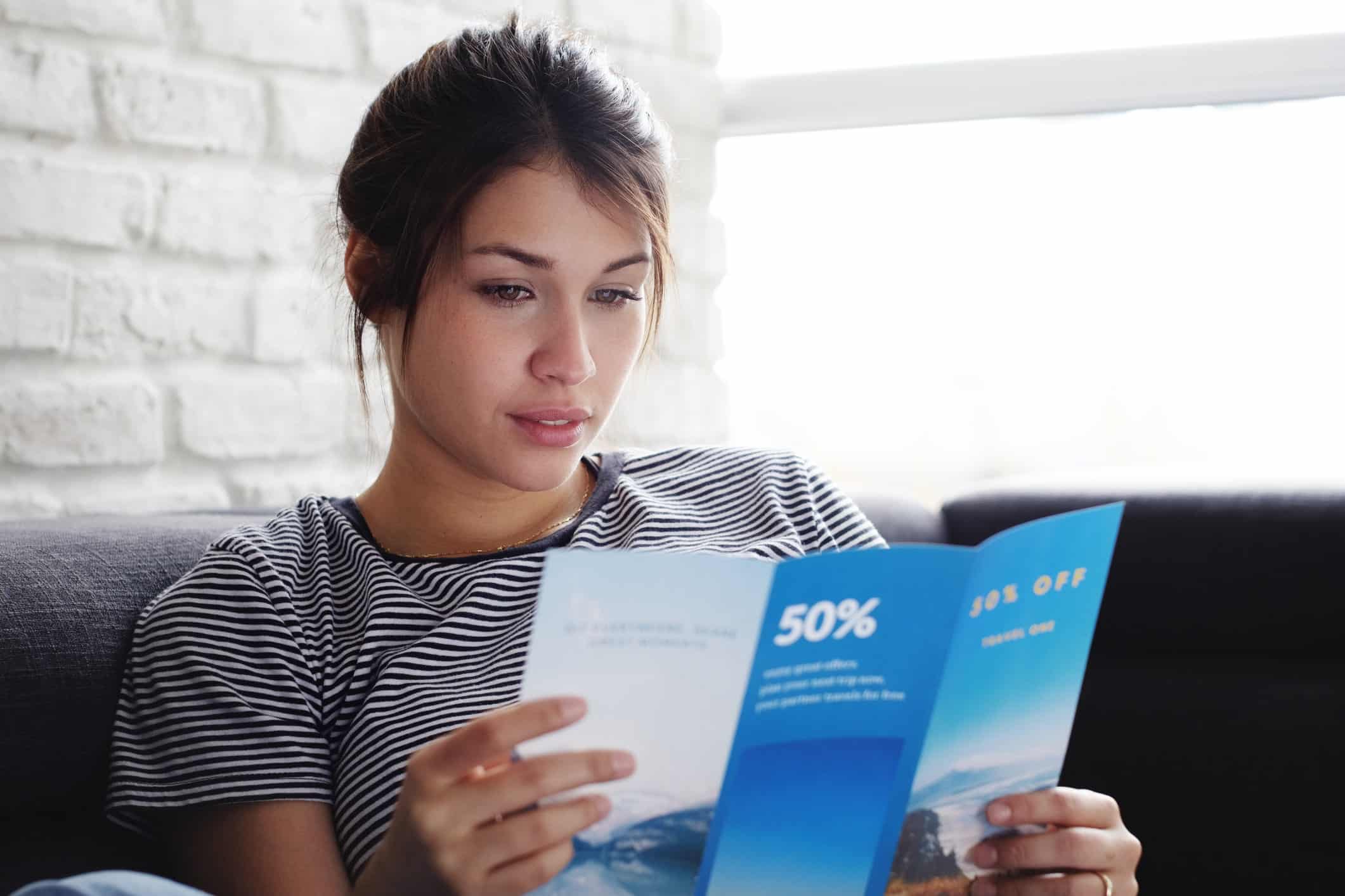 woman on sofa looking at posted brochure